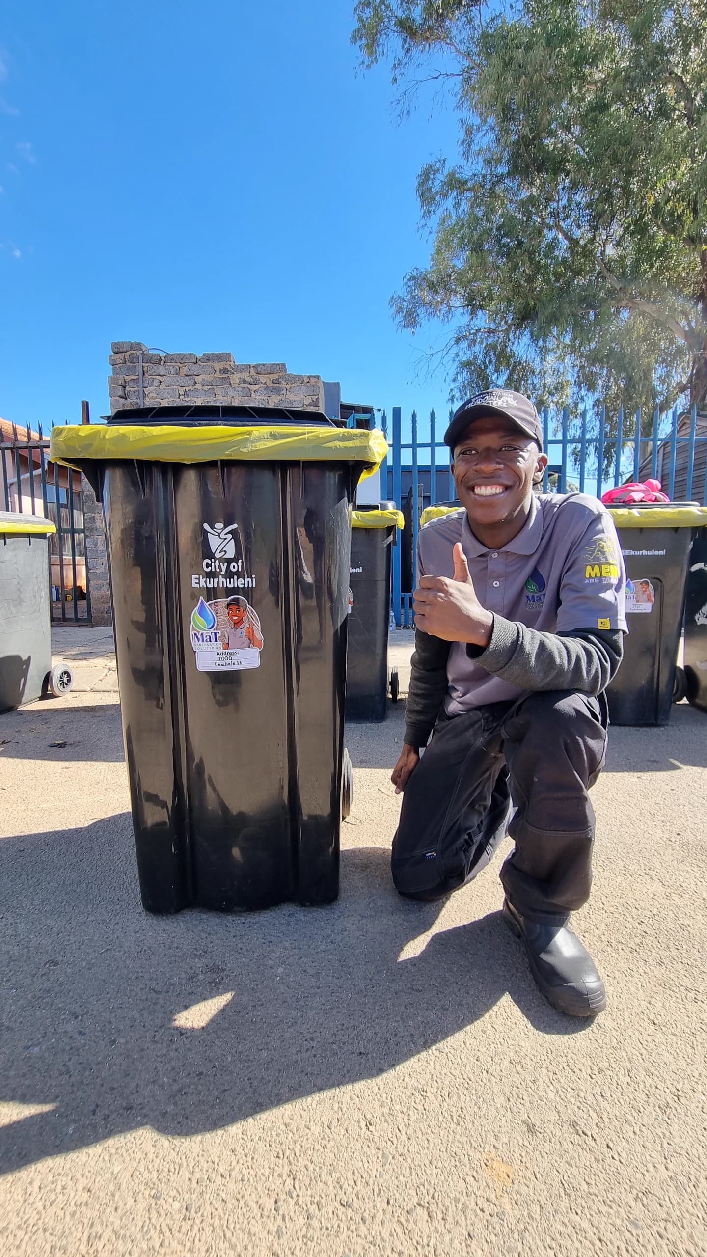 MaT team member beside a cleaned wheelie bin fitted with a fresh yellow liner