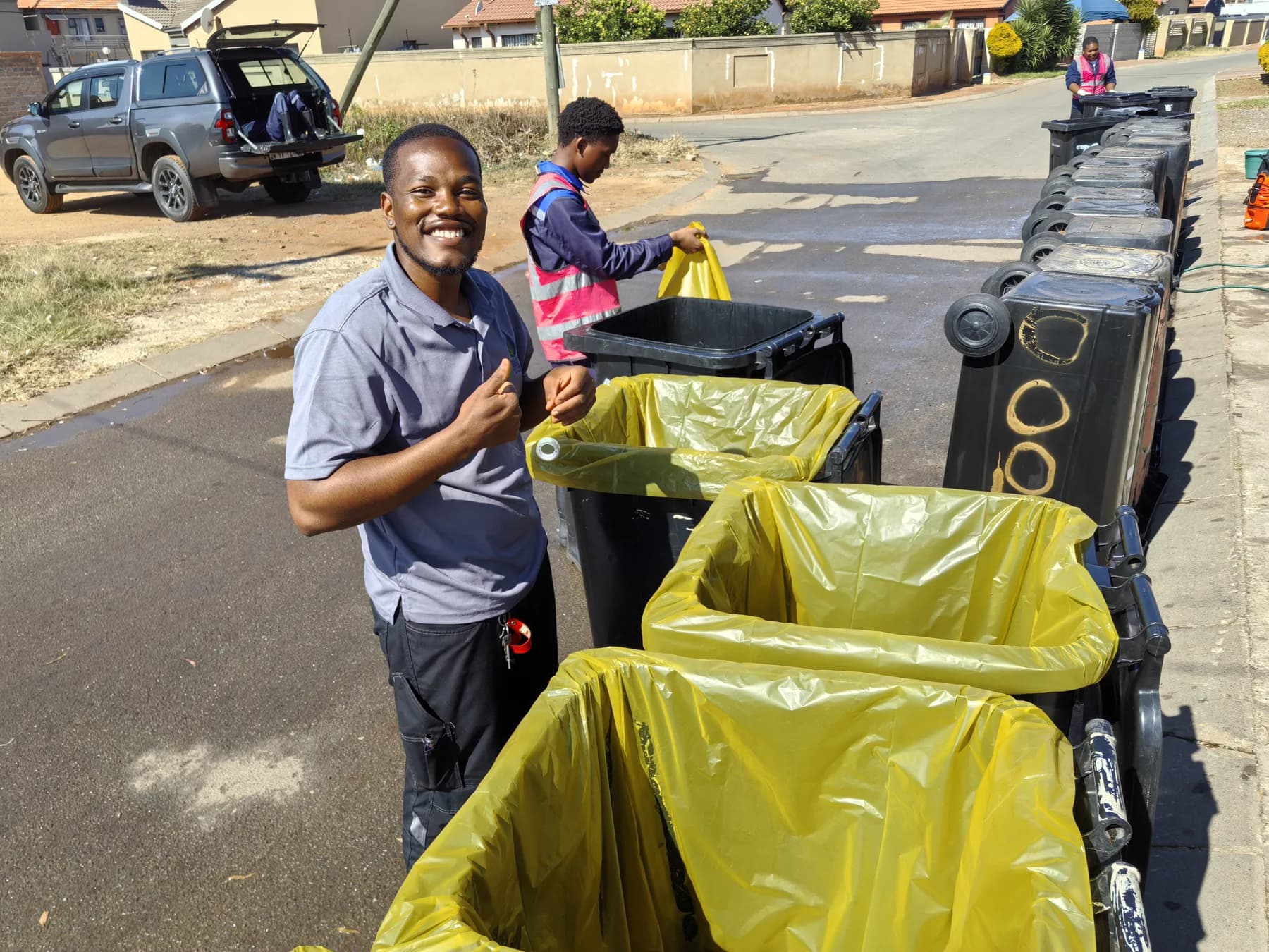 MaT team member beside a line of cleaned and lined wheelie bins